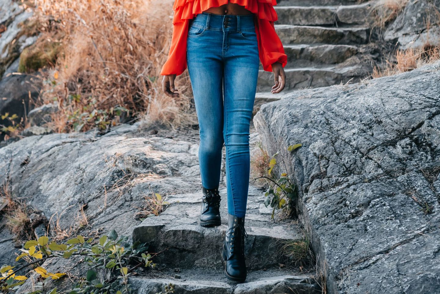 Iemand in een skinny jeans en zwarte veterboots loopt een stenen trap af